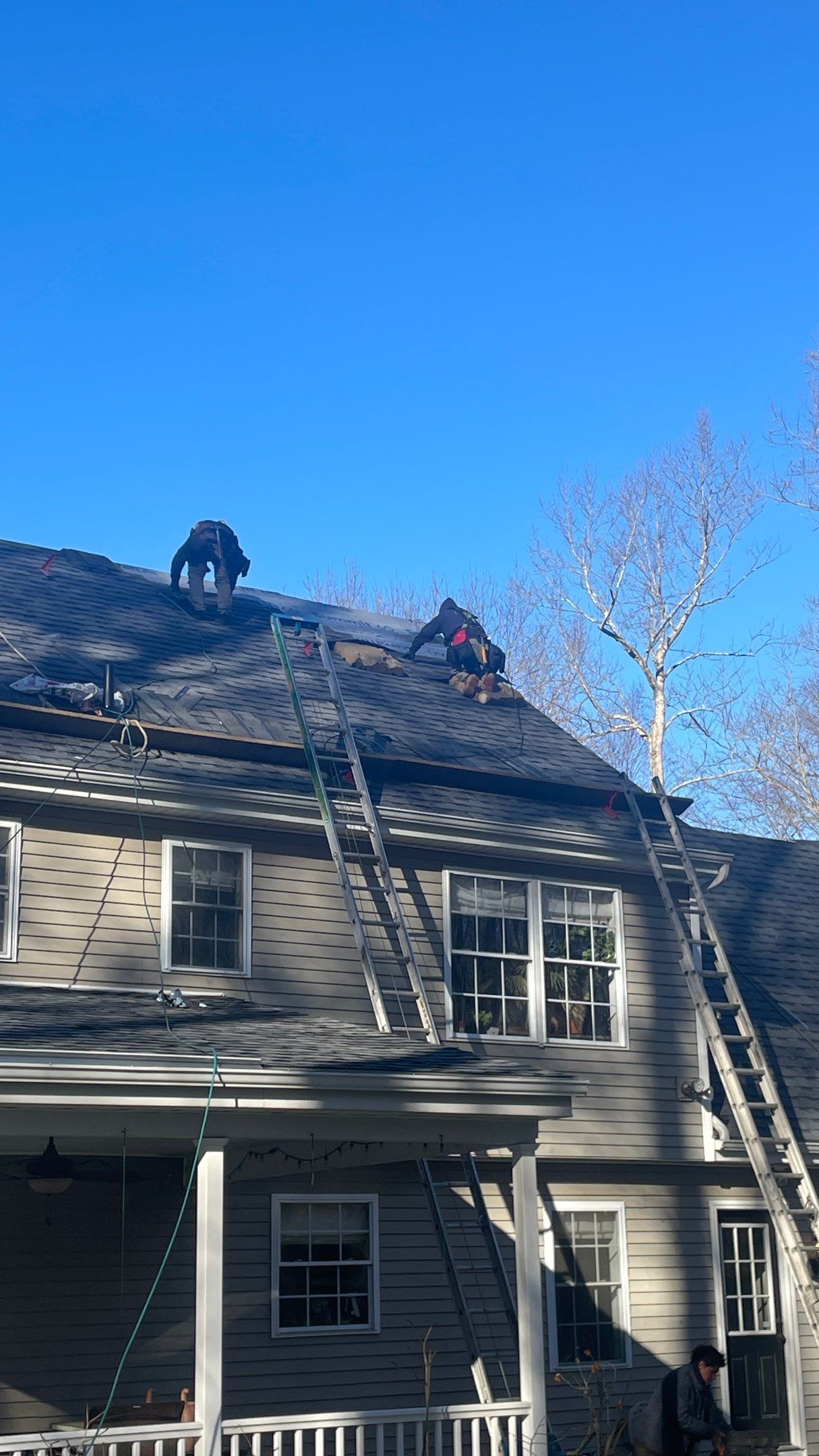 A group of people are working on the roof of a house.
