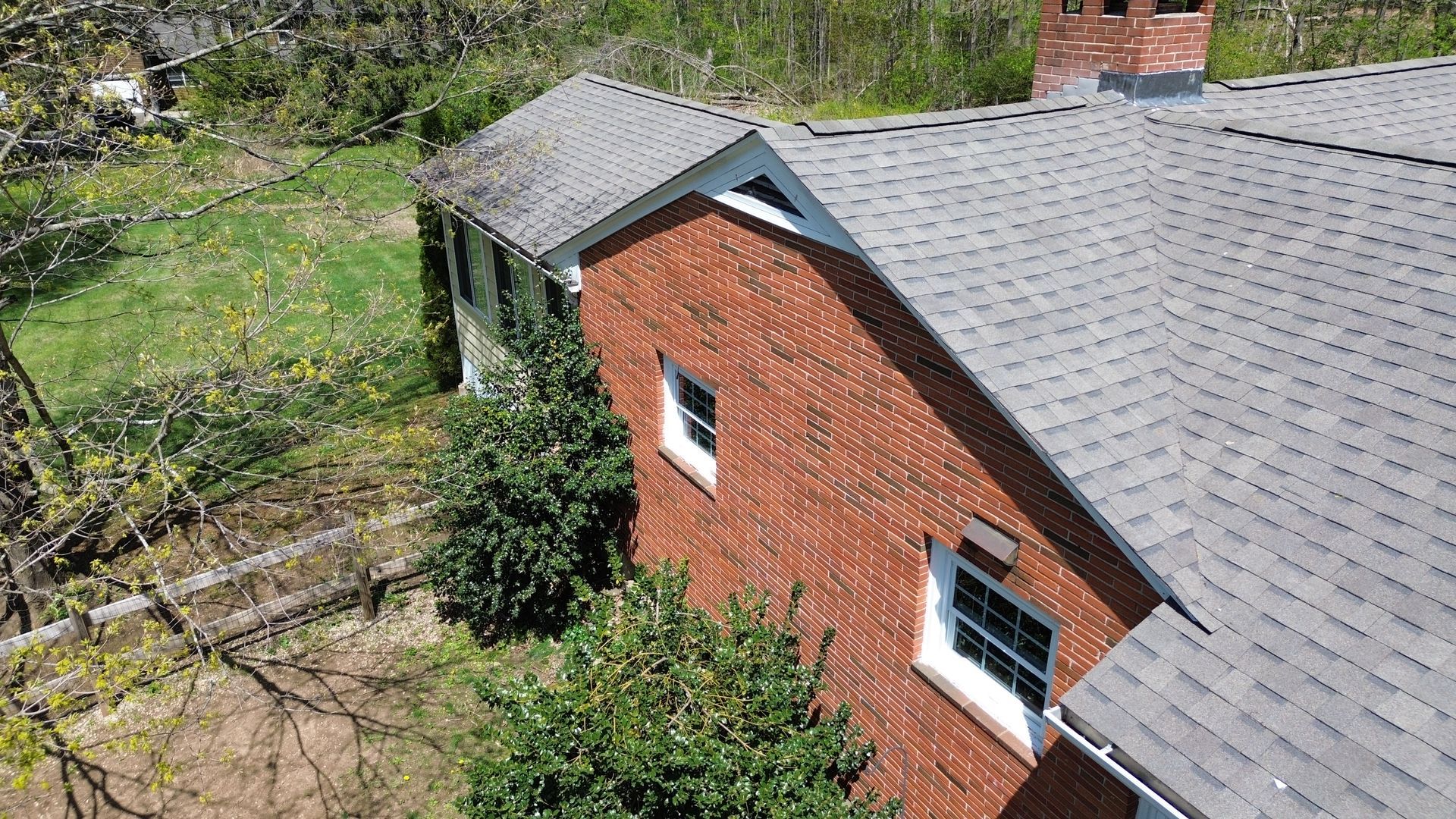 An aerial view of a brick house with a roof and a chimney.