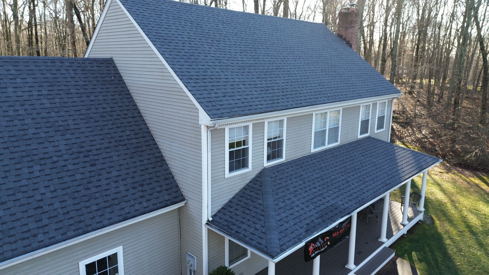 An aerial view of a house with a blue roof and a porch.