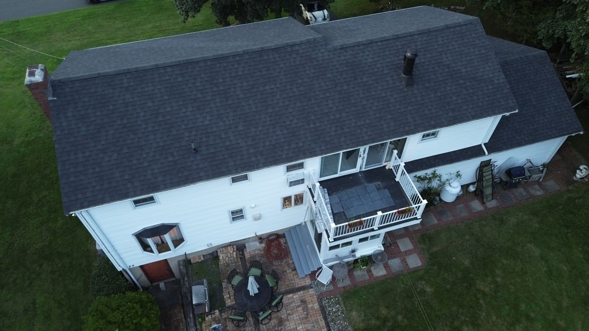 An aerial view of a large white house with a black roof.