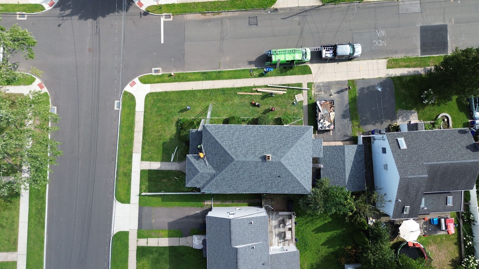 An aerial view of a residential neighborhood with a garbage truck parked on the side of the road.