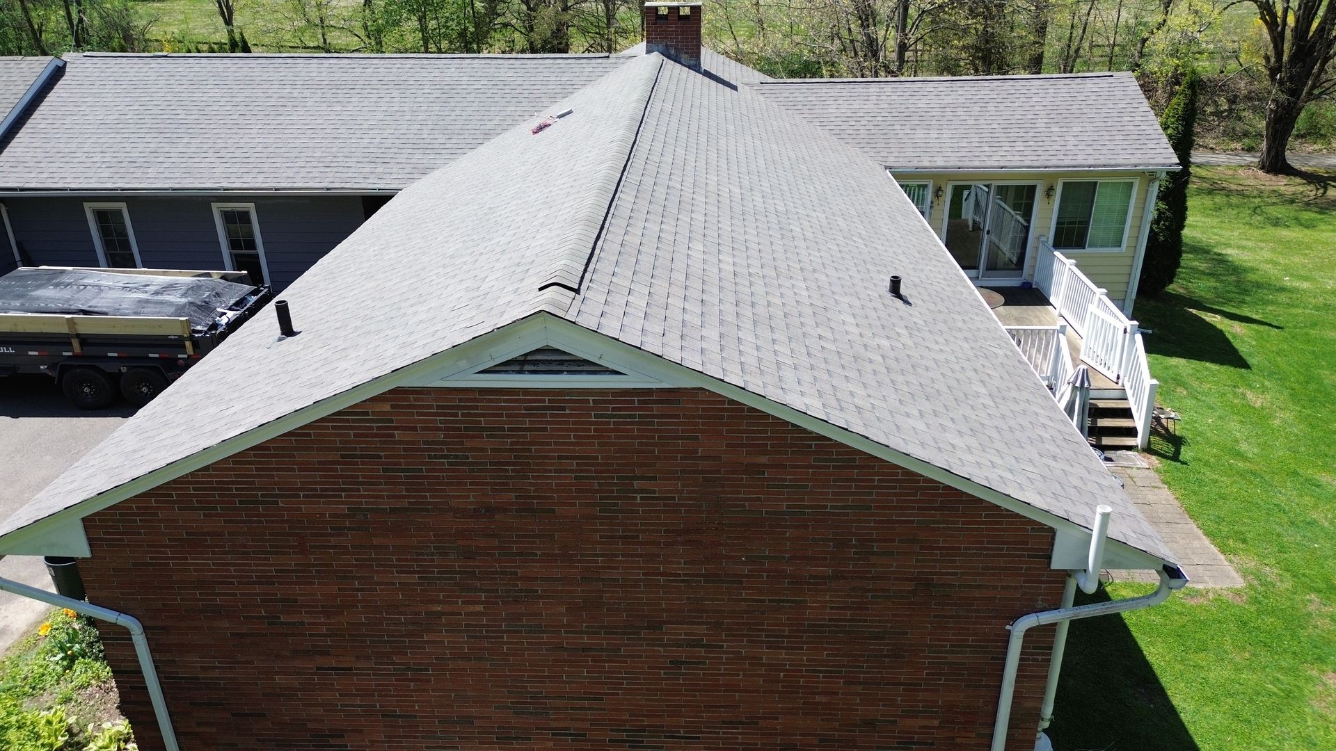 An aerial view of a brick house with a new roof.