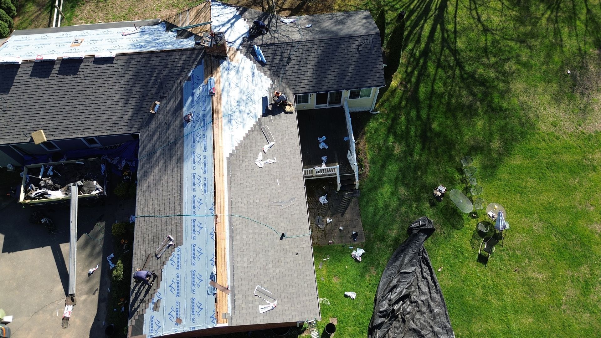 An aerial view of a house under construction with a roof being installed.