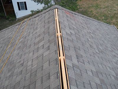 An aerial view of a roof with shingles being installed.