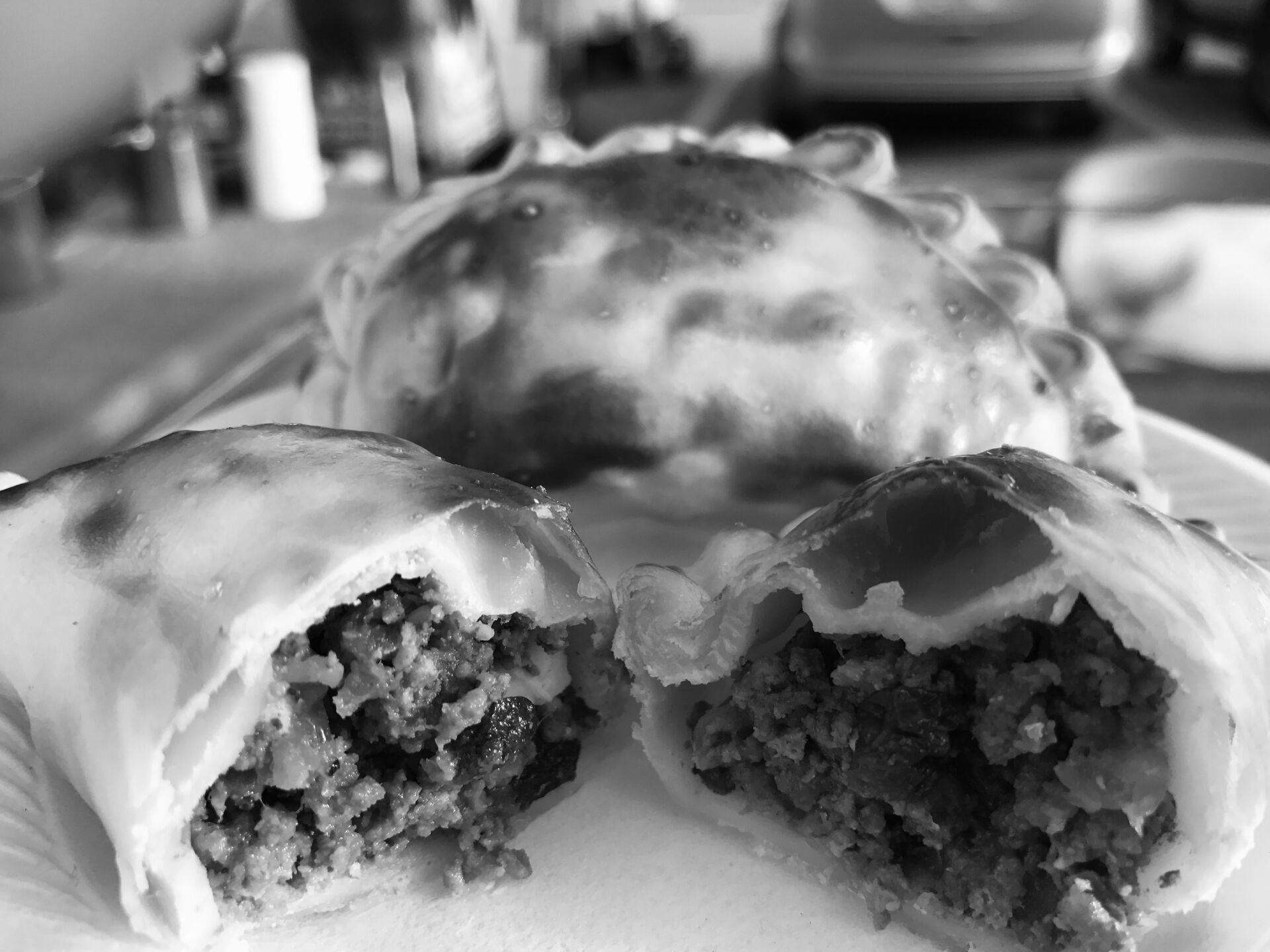 Empanadas on a plate; one cut open, revealing a ground meat filling.