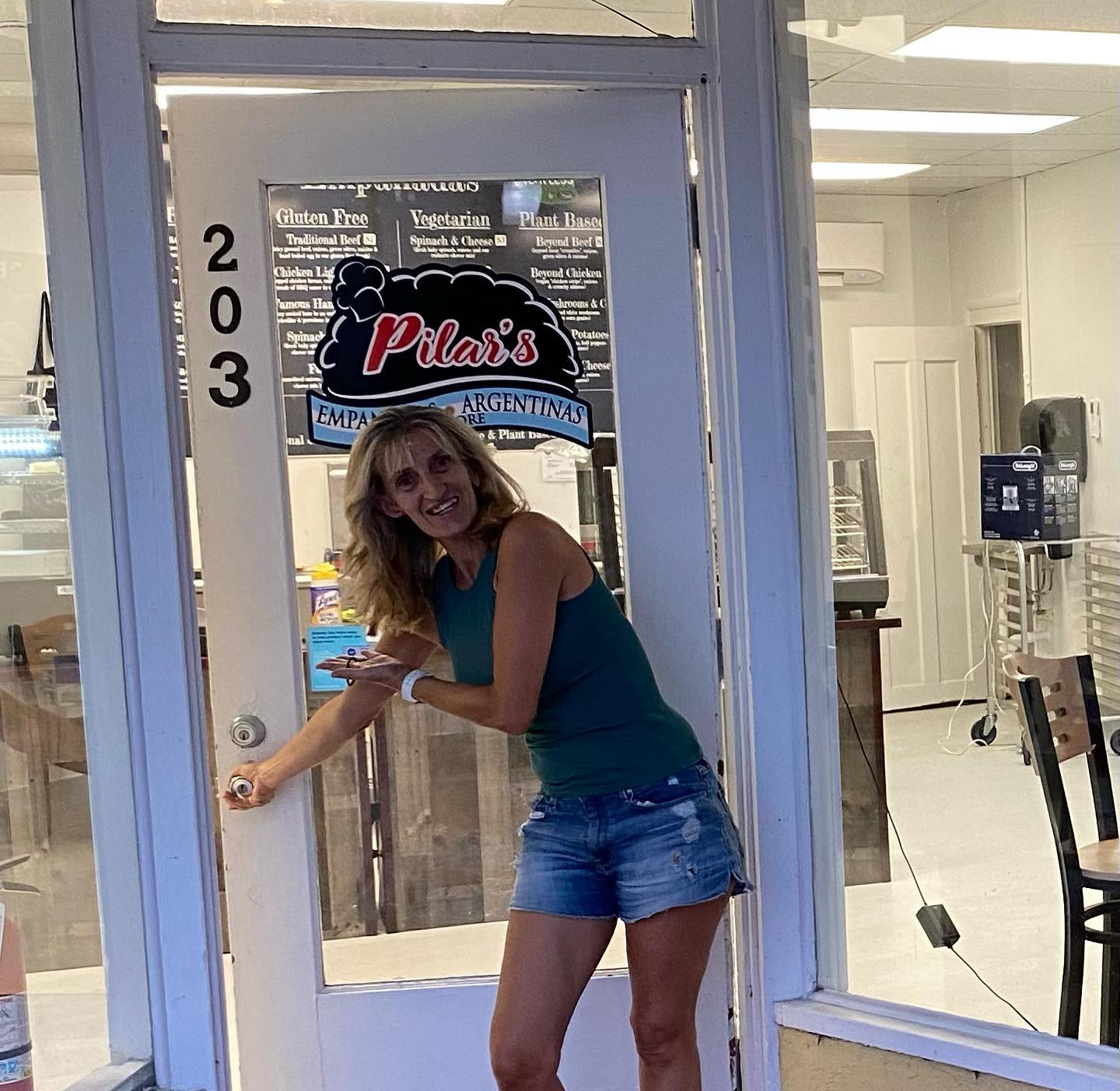 Woman in shorts and tank top opening the door to Pilar's shop at 203.