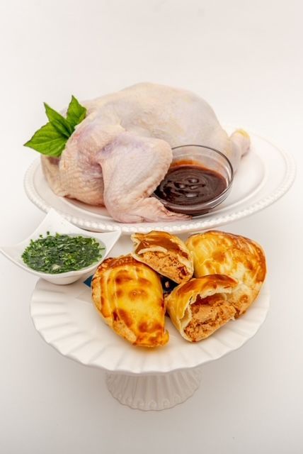Raw chicken, dipping sauce, and empanadas on serving plates.