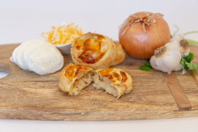 Savory pastries with onion, garlic, cheese, and cream cheese on a wooden board.
