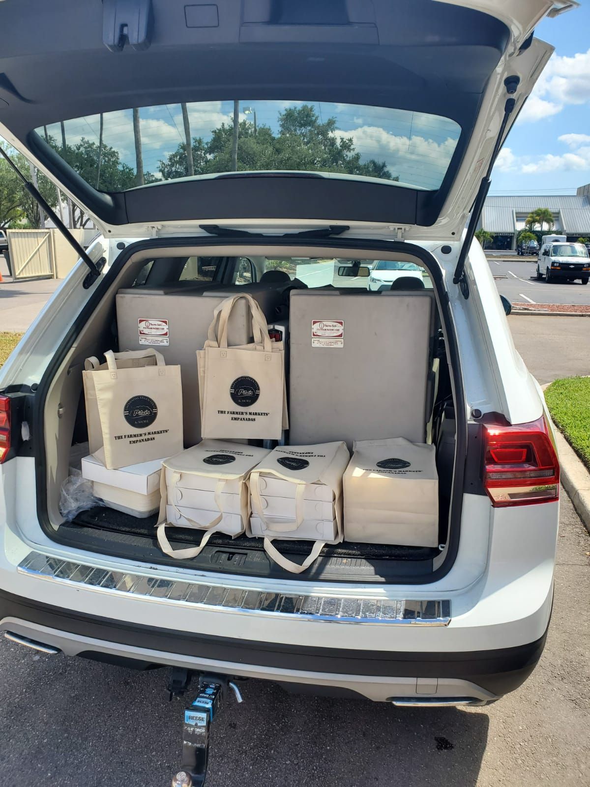 A white SUV with its trunk open, packed with boxes and tote bags.