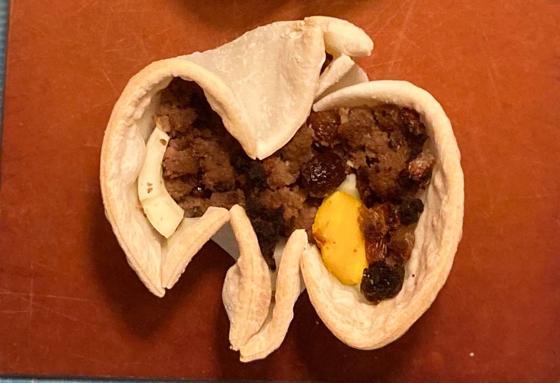 Cut-open empanada with meat and egg filling on a cutting board.