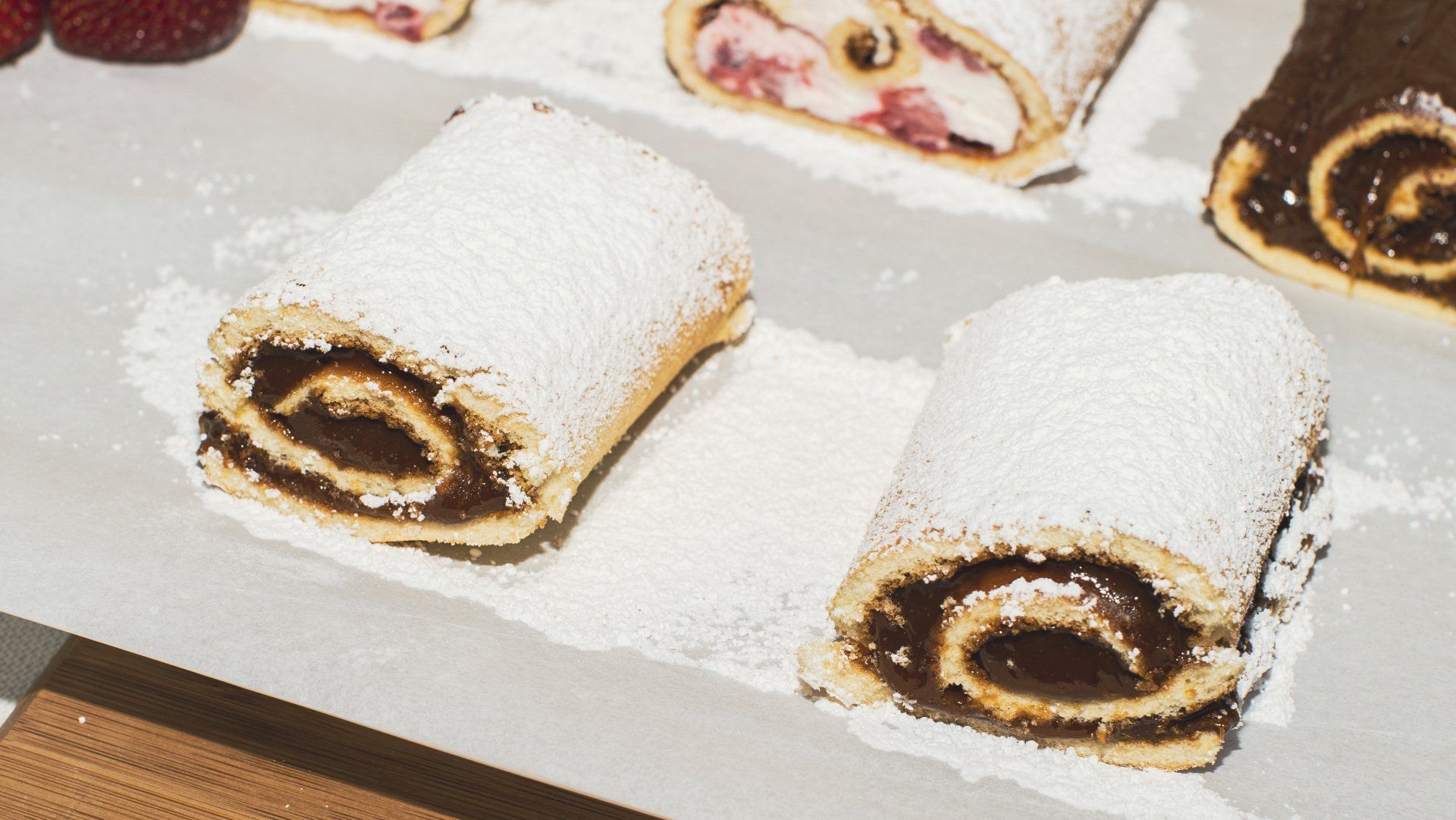 Two chocolate-filled, rolled pastries dusted with powdered sugar on a white surface.