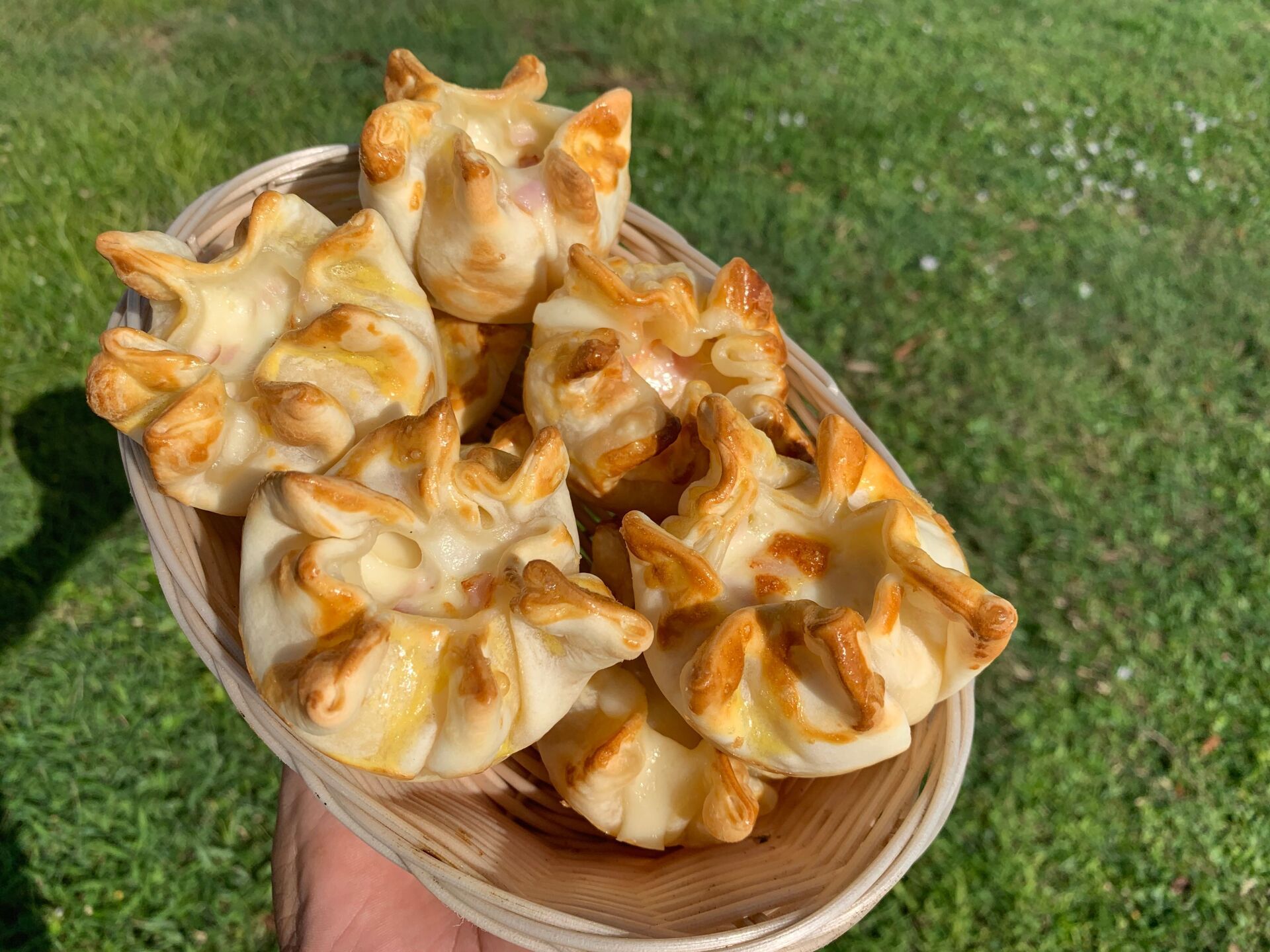 Basket of baked pastries outdoors, golden brown with crimped edges.
