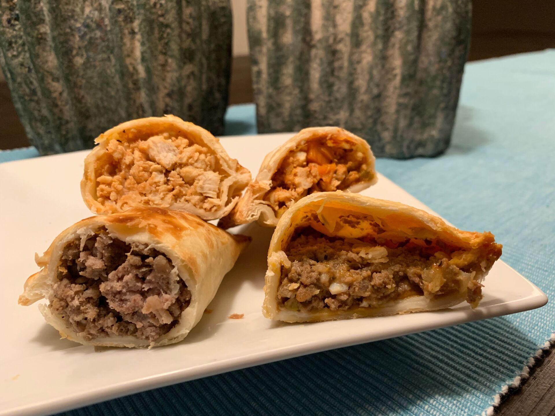 Four empanadas on a white plate, two cut open to reveal meat fillings.