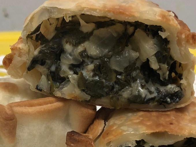 Spinach and cheese hand pie, cut open to reveal filling.