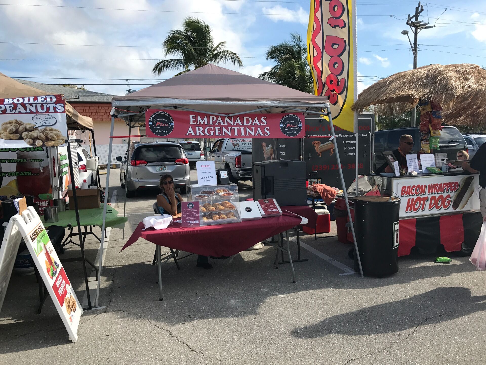 Food vendors at an outdoor market: empanadas, hot dogs, and boiled peanuts. Sunny day.