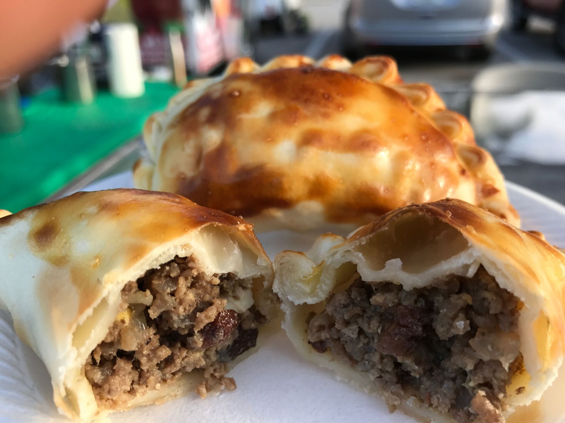 Close-up of two golden brown empanadas; one halved, revealing meat filling.