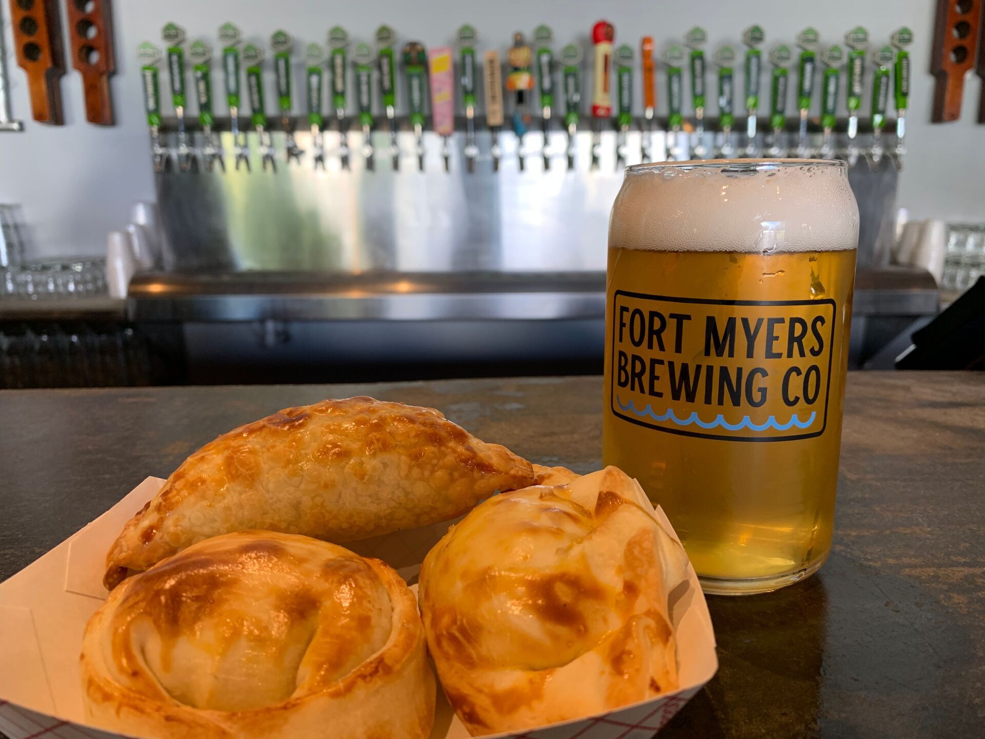 Glass of beer from Fort Myers Brewing Co. with empanadas at a bar.