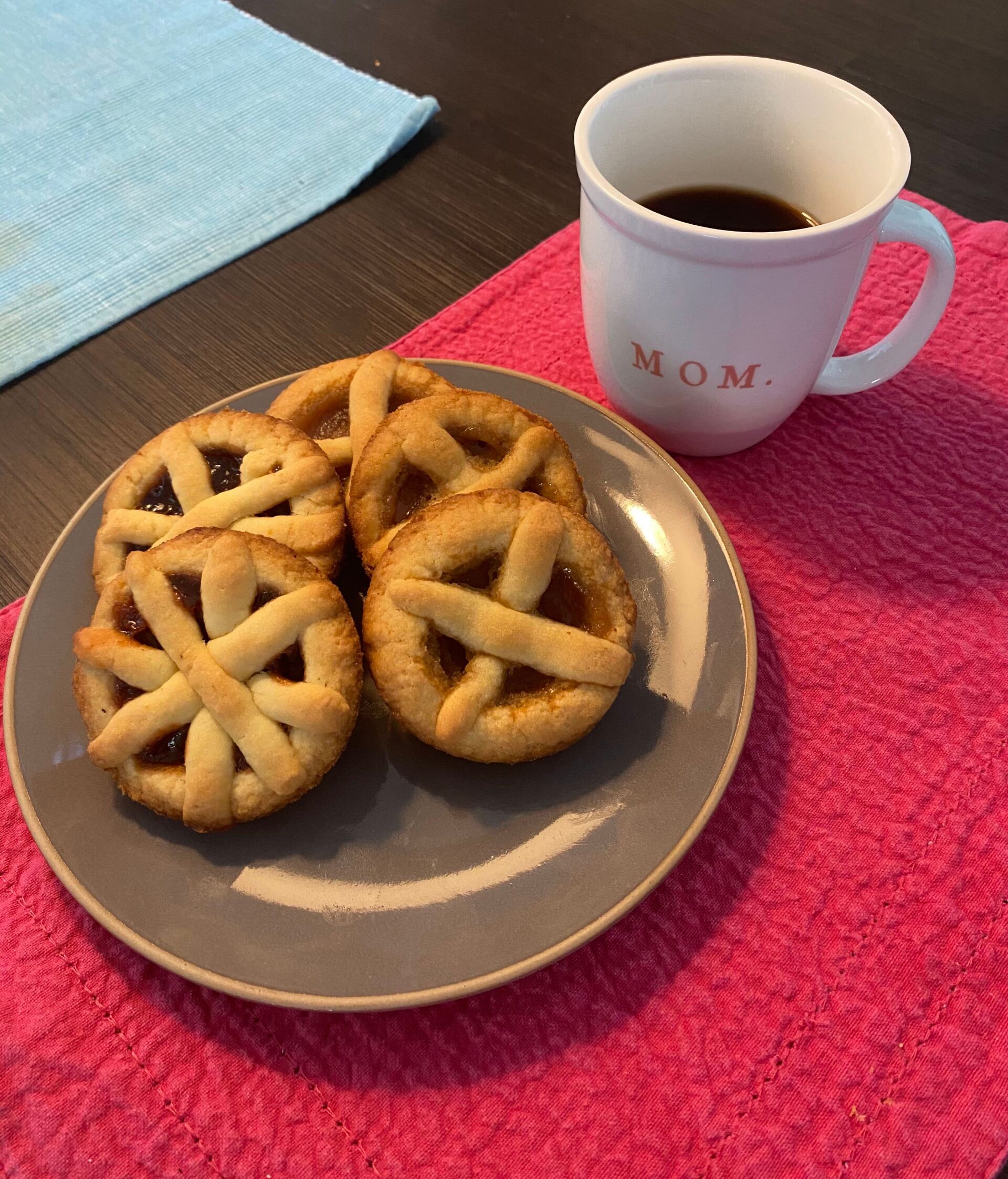 A plate with pastries, next to a mug of coffee on a table.