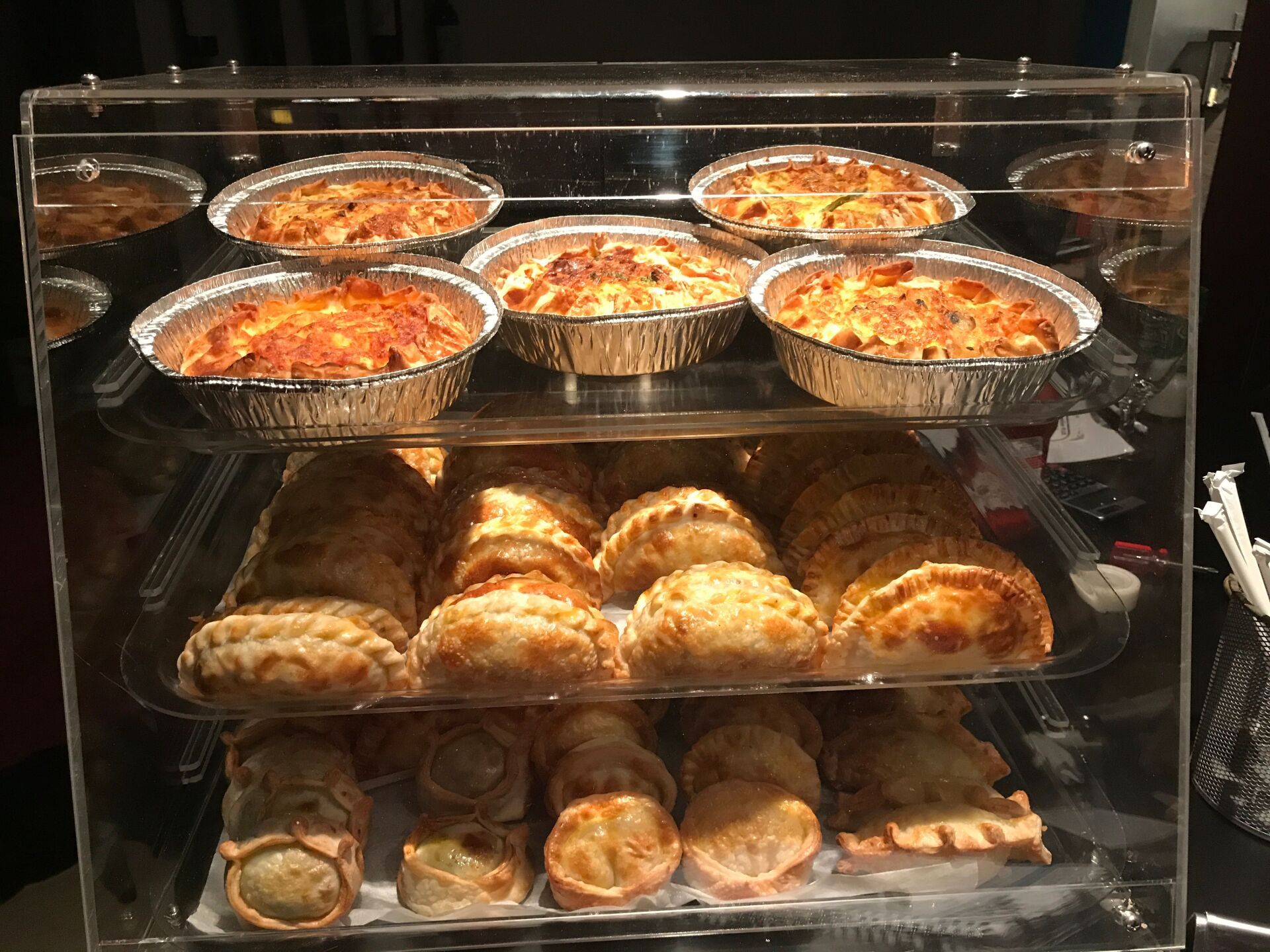 Display case with baked goods, including savory pies and empanadas.