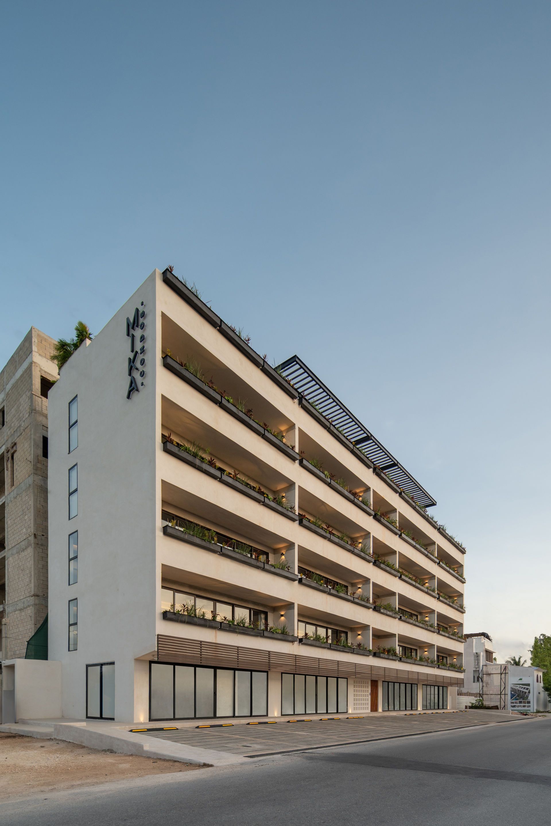 Un gran edificio blanco con muchos balcones está situado al costado de una carretera.