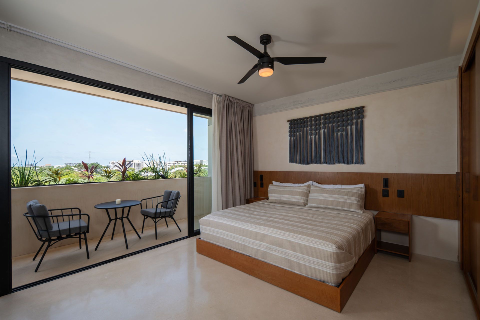 Un dormitorio con una cama king size y un balcón con mesa y sillas.