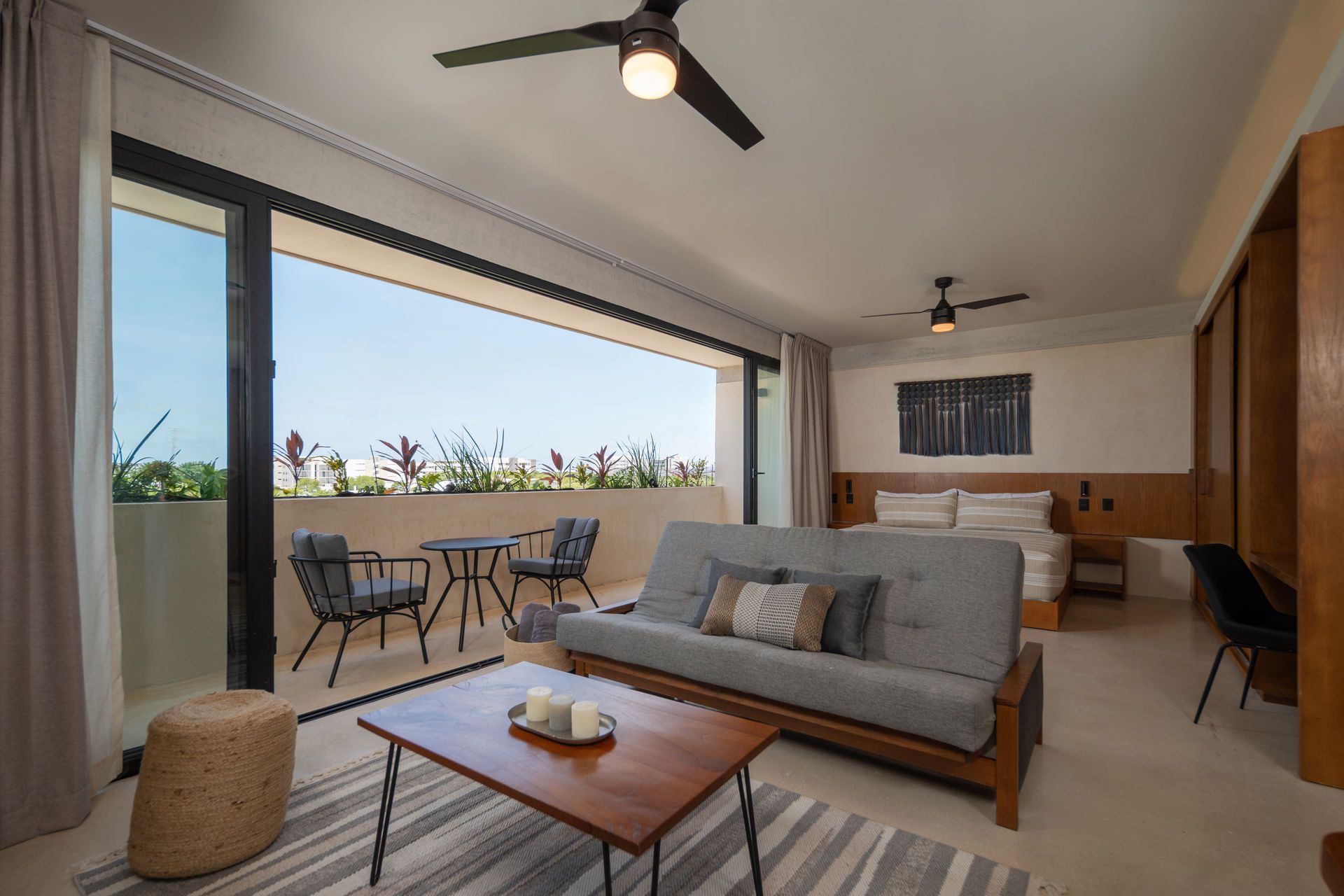 Una sala de estar con sofá, mesa de café, sillas y balcón.