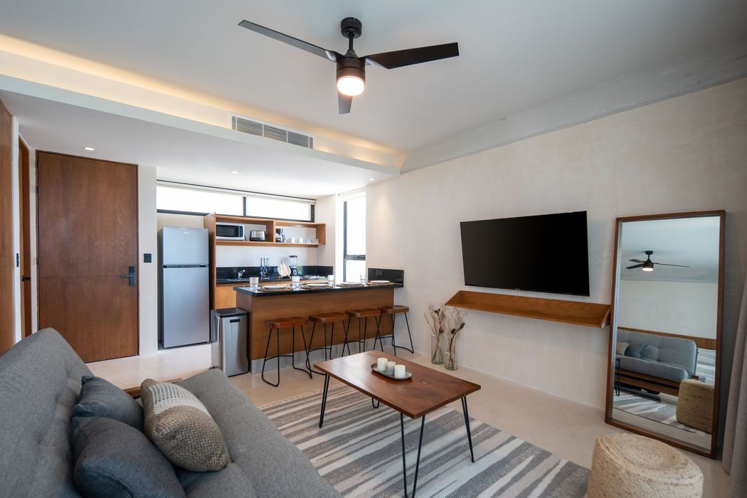 Una sala de estar con ventilador de techo y televisor de pantalla plana.