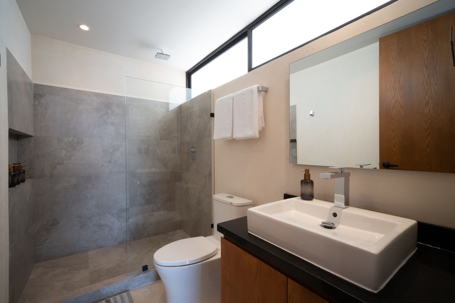 Un baño con inodoro, lavabo, espejo y ducha.