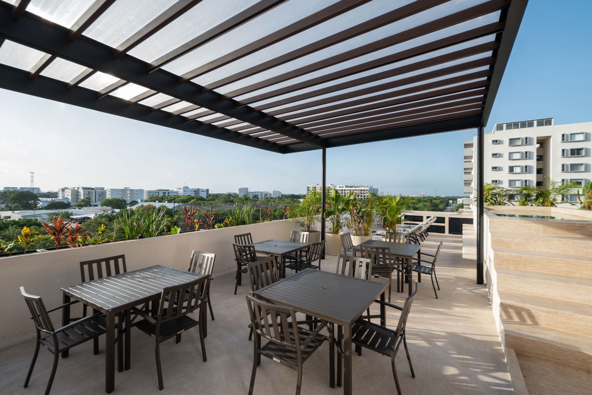 Un patio con mesas y sillas bajo una pérgola.