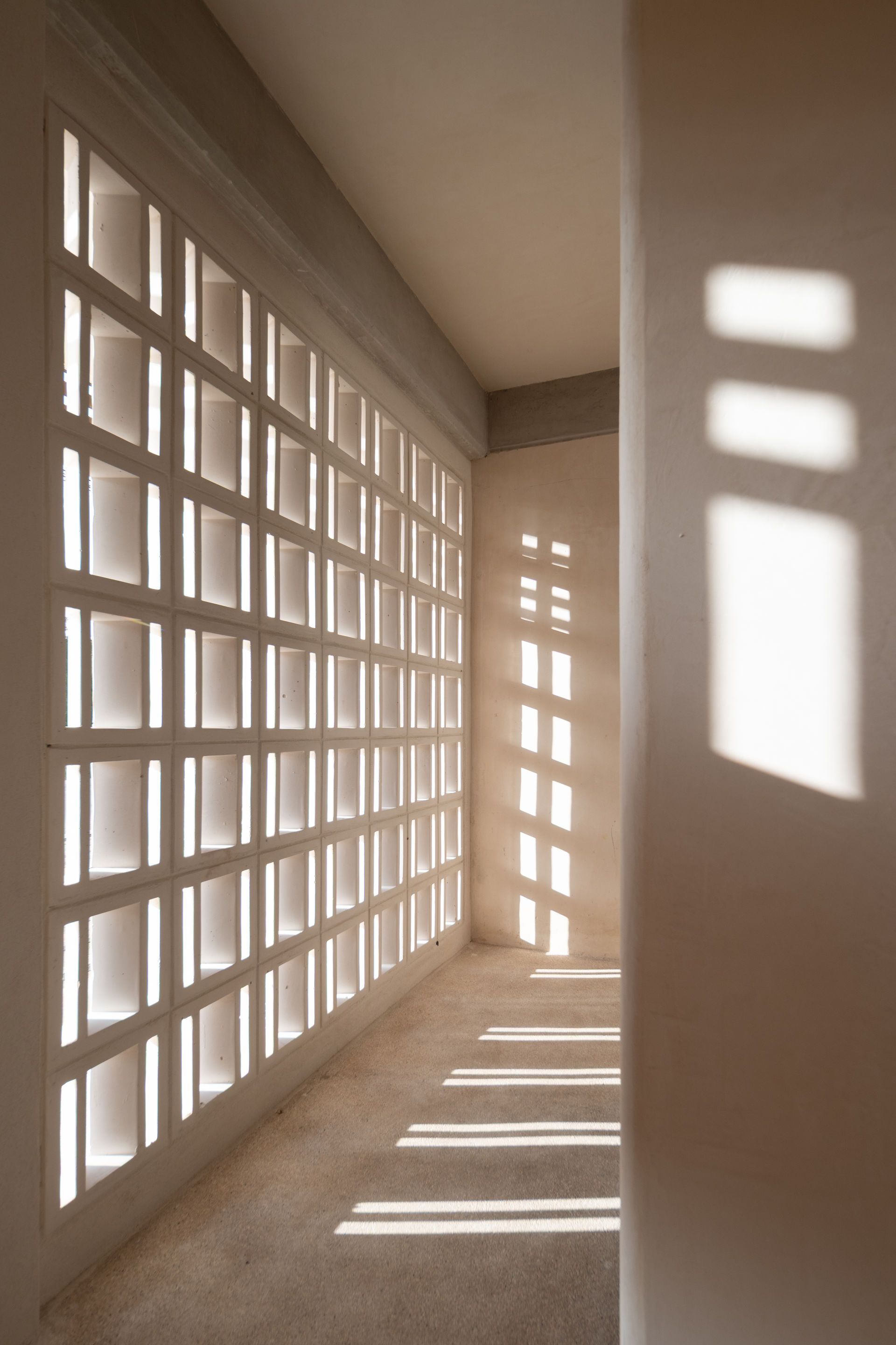 Un pasillo con muchas ventanas y sombras en la pared.