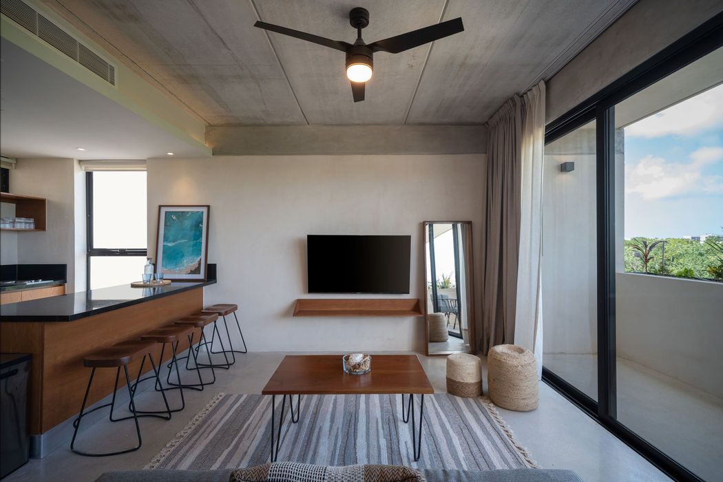 Una sala de estar con un televisor de pantalla plana en la pared y un ventilador de techo.