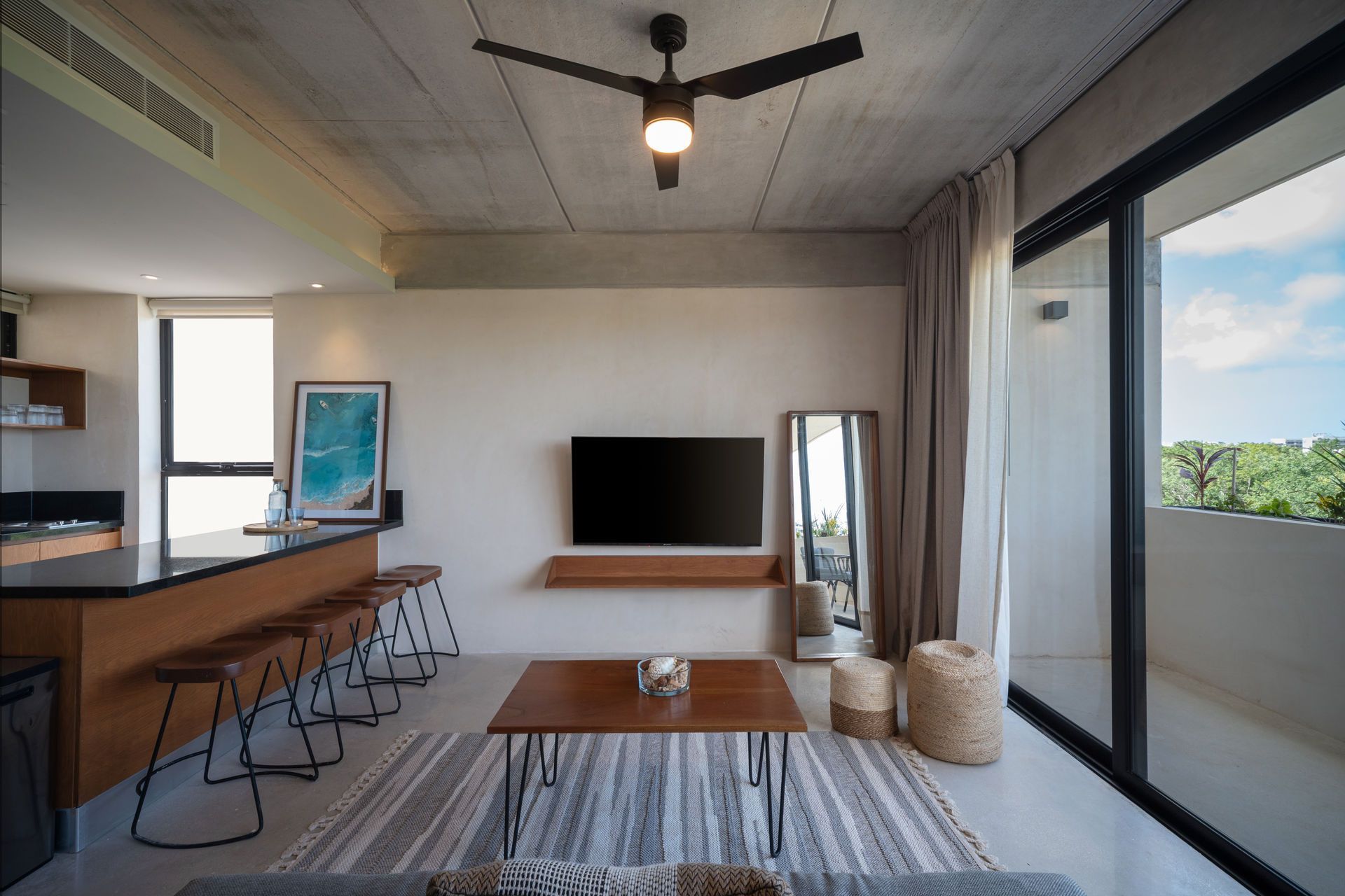 Una sala de estar con un televisor de pantalla plana en la pared y un ventilador de techo.