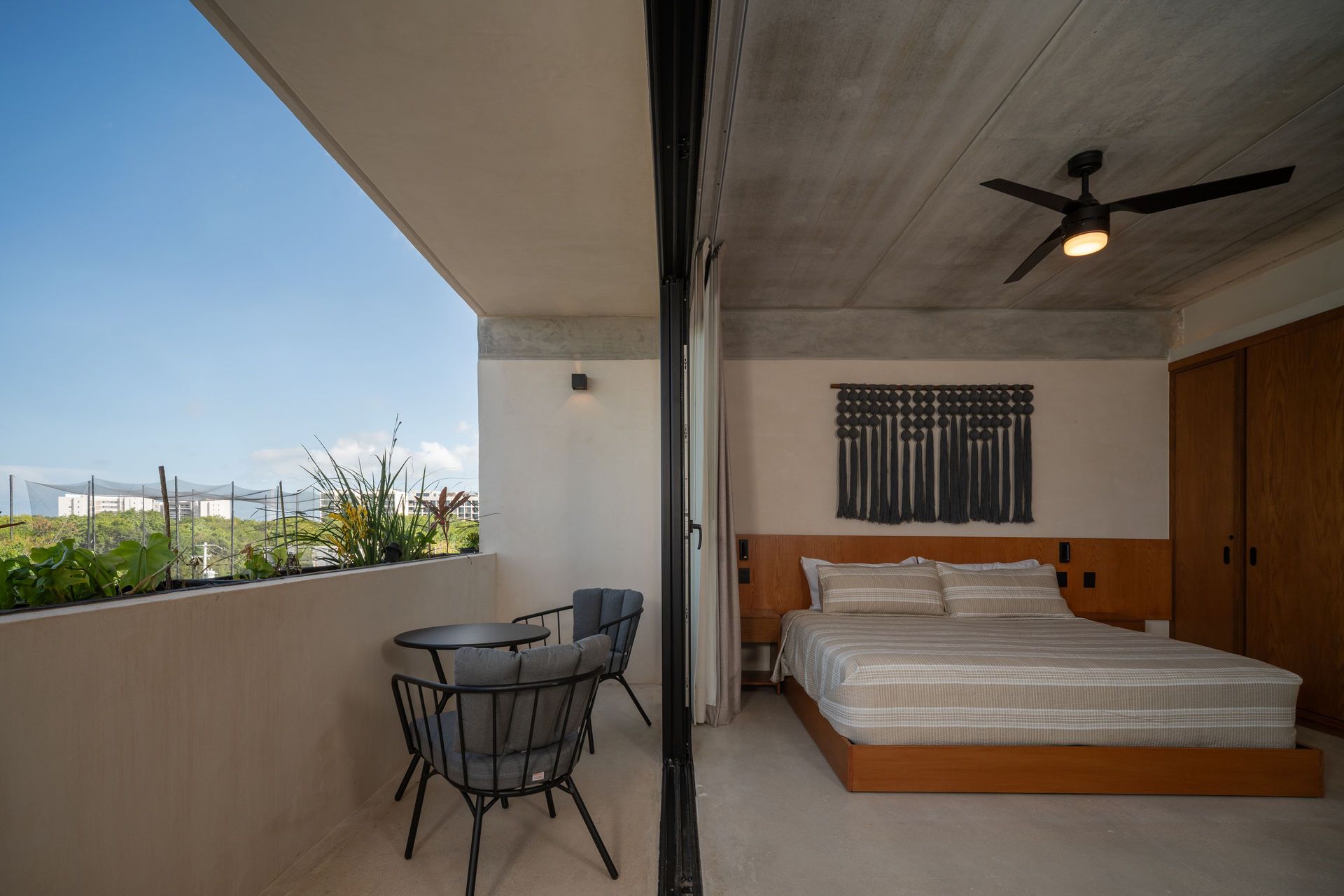 Un dormitorio con una cama grande y un balcón con mesa y sillas.