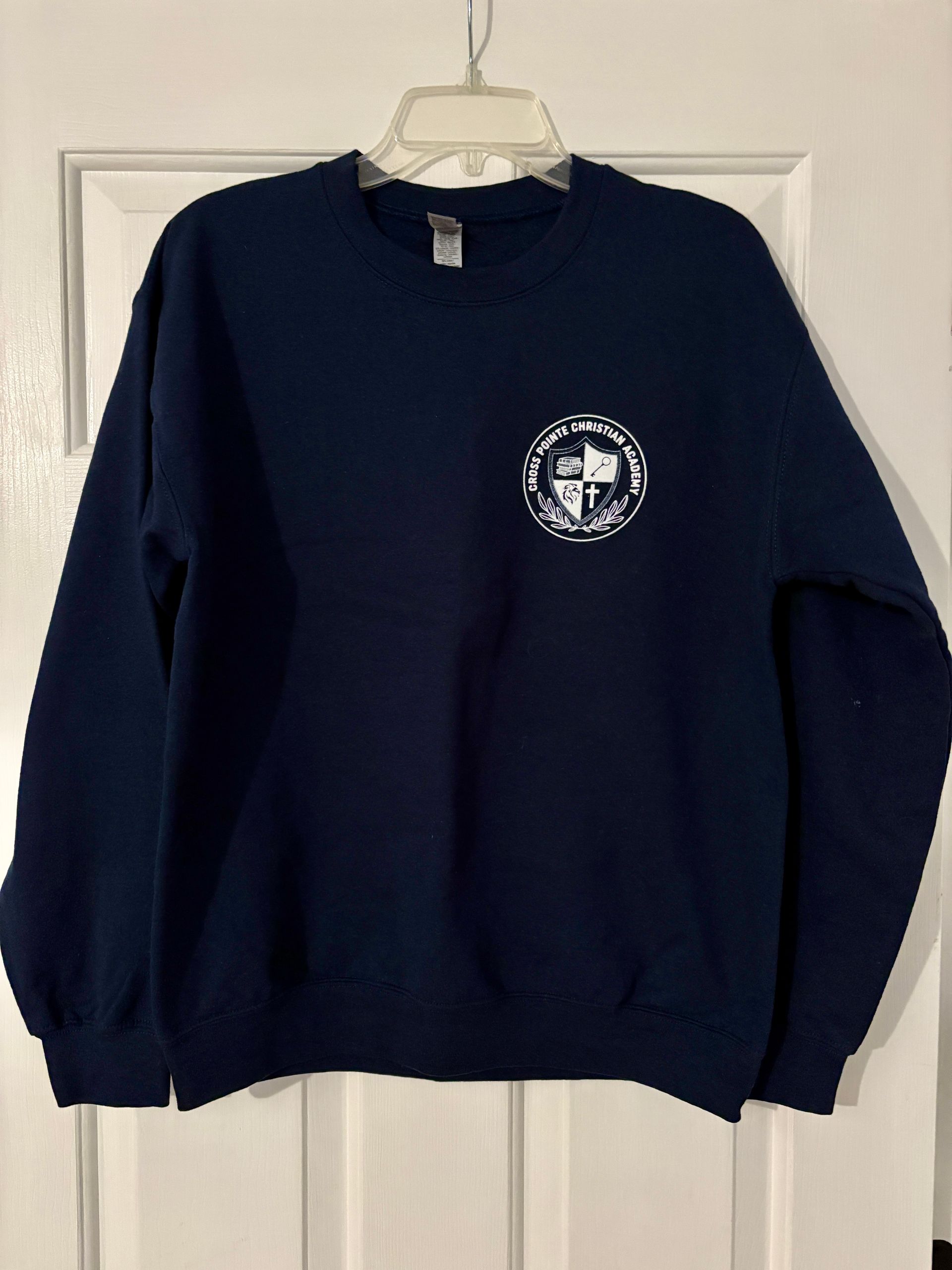 Navy blue sweatshirt with a white emblem on a white hanger.
