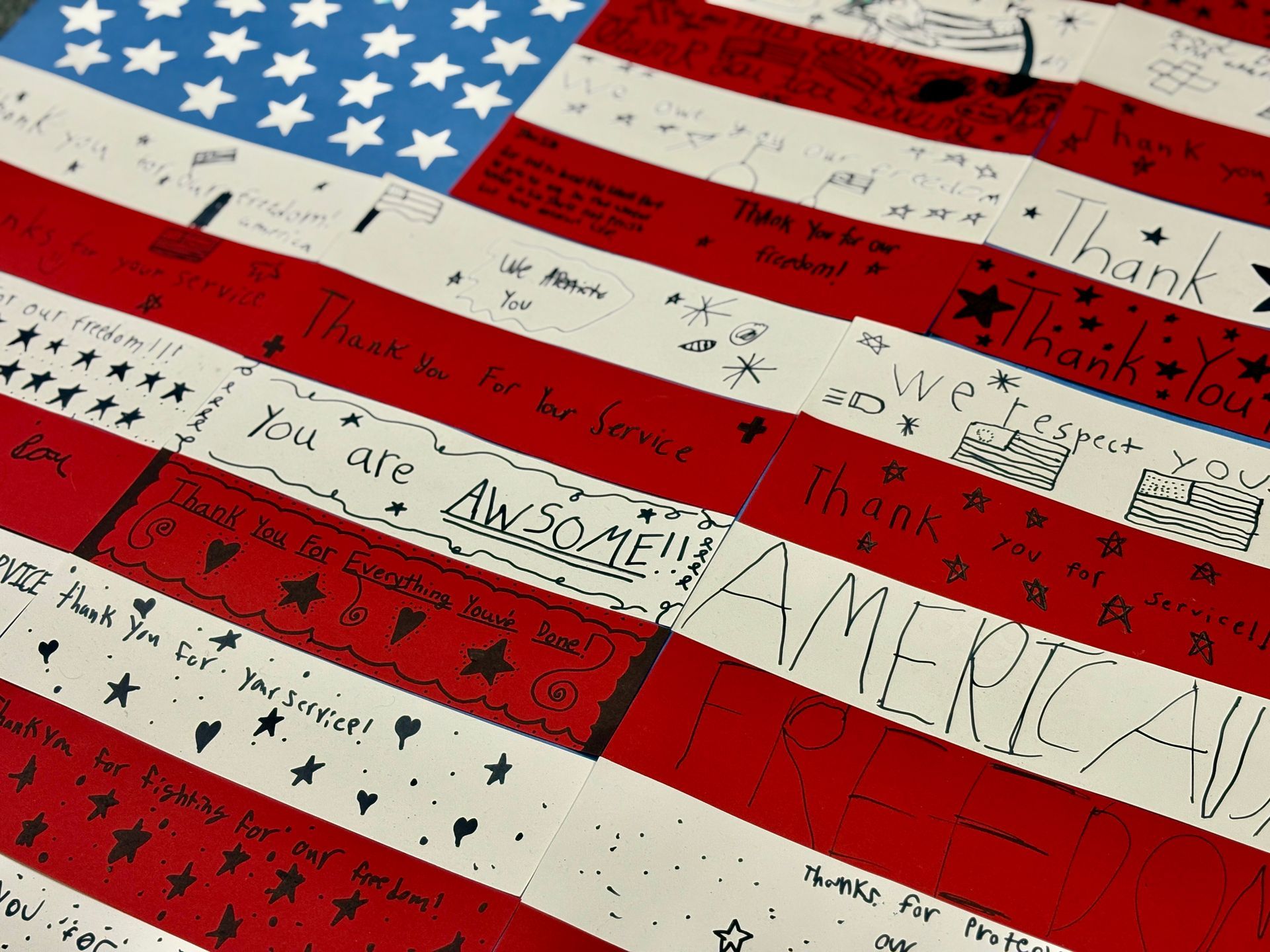 American flag made of red and white stripes; each stripe is filled with handwritten messages. Blue field with white stars.