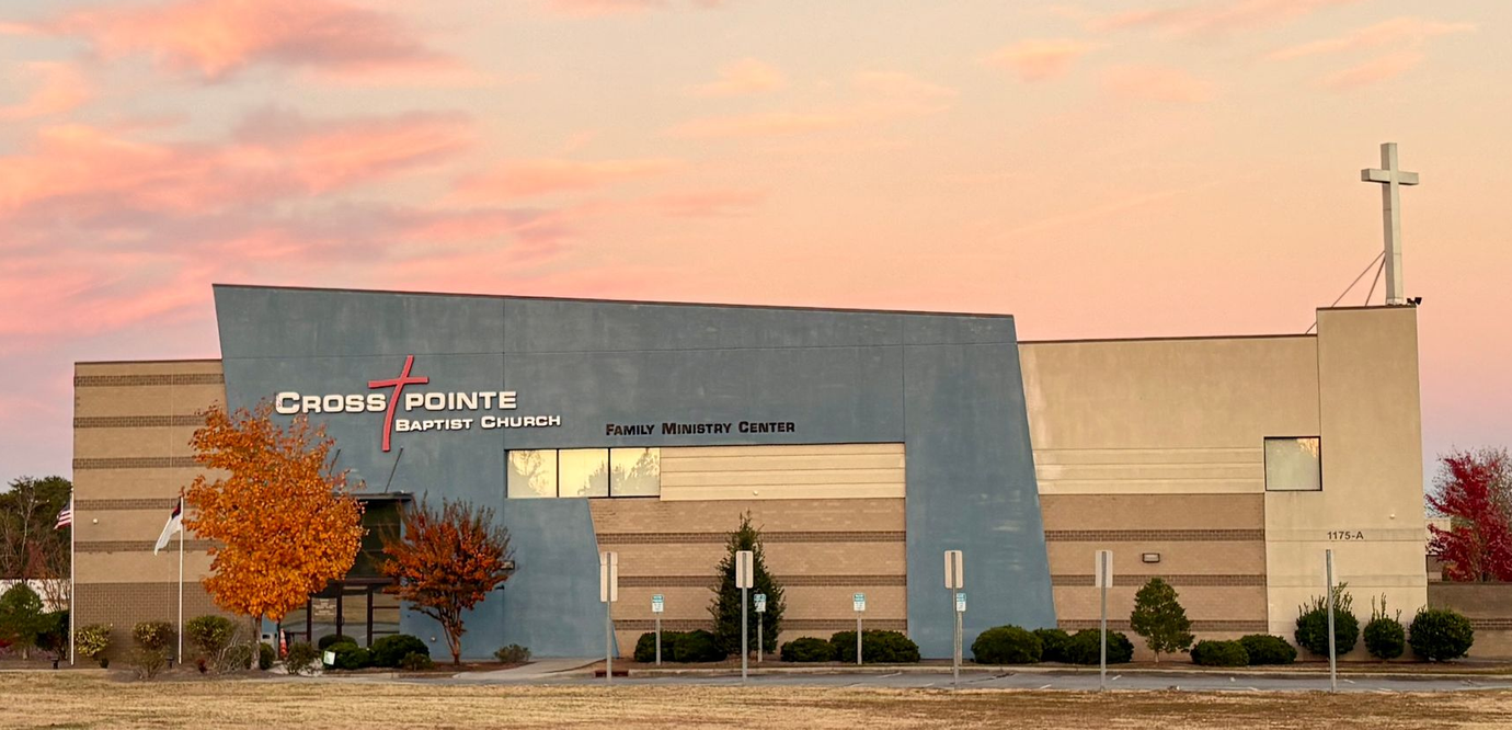 Church Point Community Church building with a cross on top. Autumn trees and a colorful sunset.