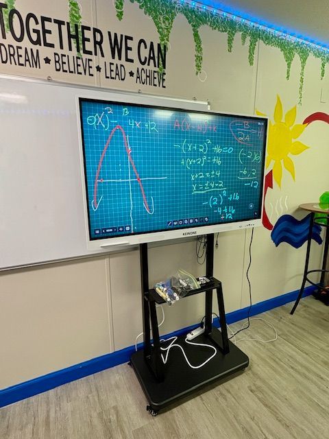 Interactive whiteboard with math equations displayed, in a classroom setting.