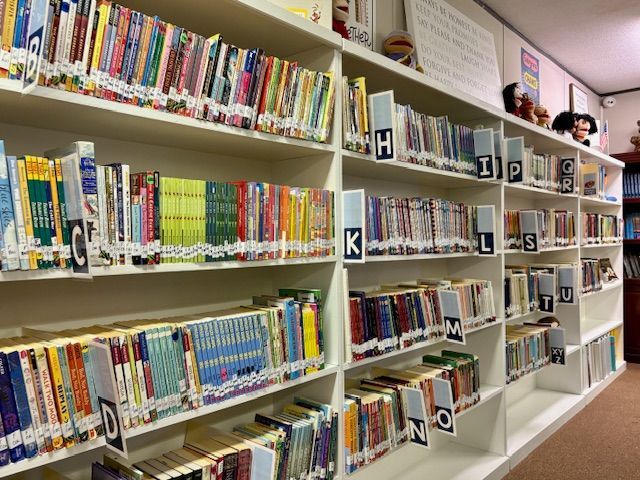 Interior of a library with bookshelves and a large table surrounded by chairs.