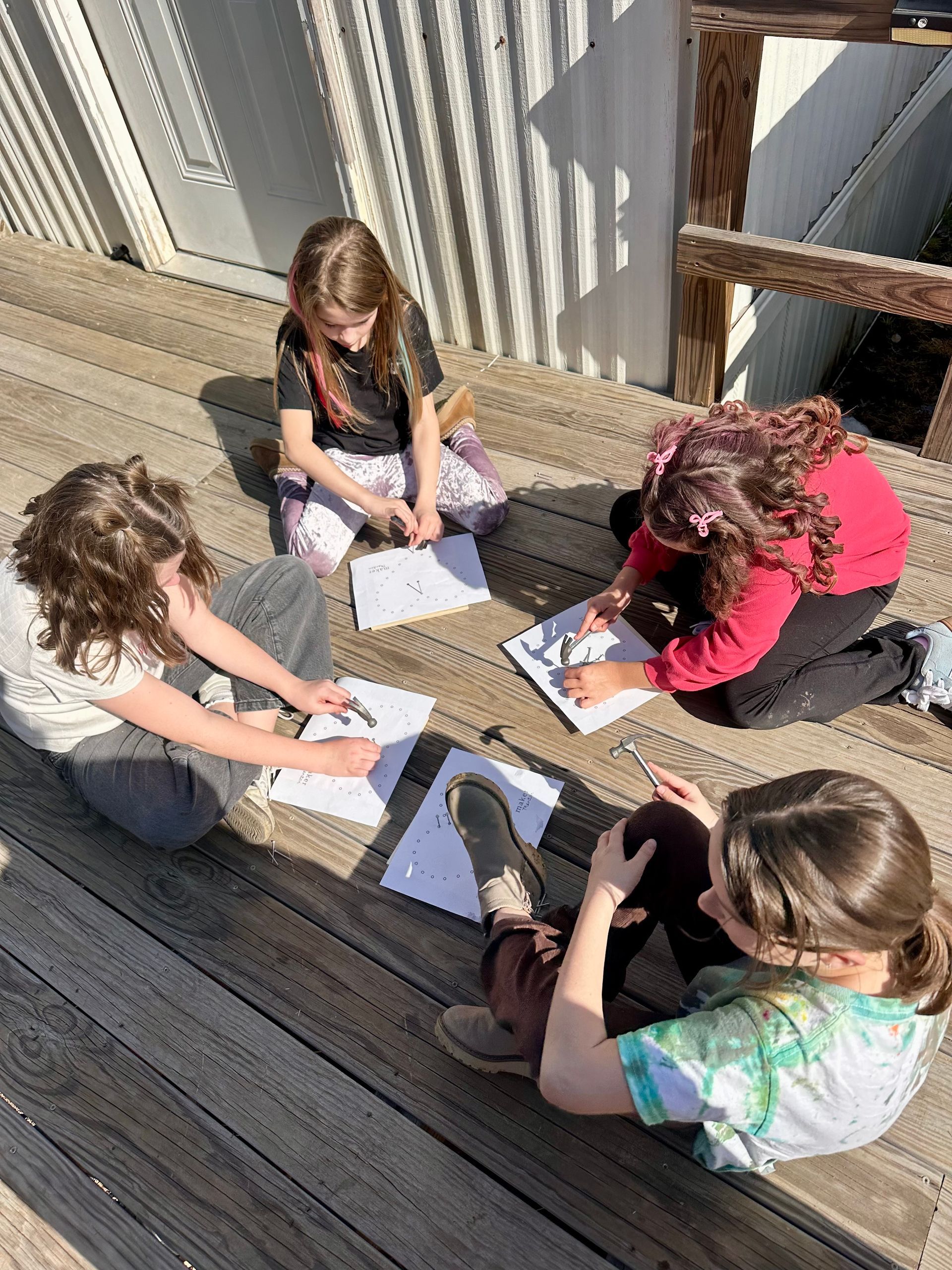 Four people in pajamas pose in a classroom. Two children and an adult smile at the camera.