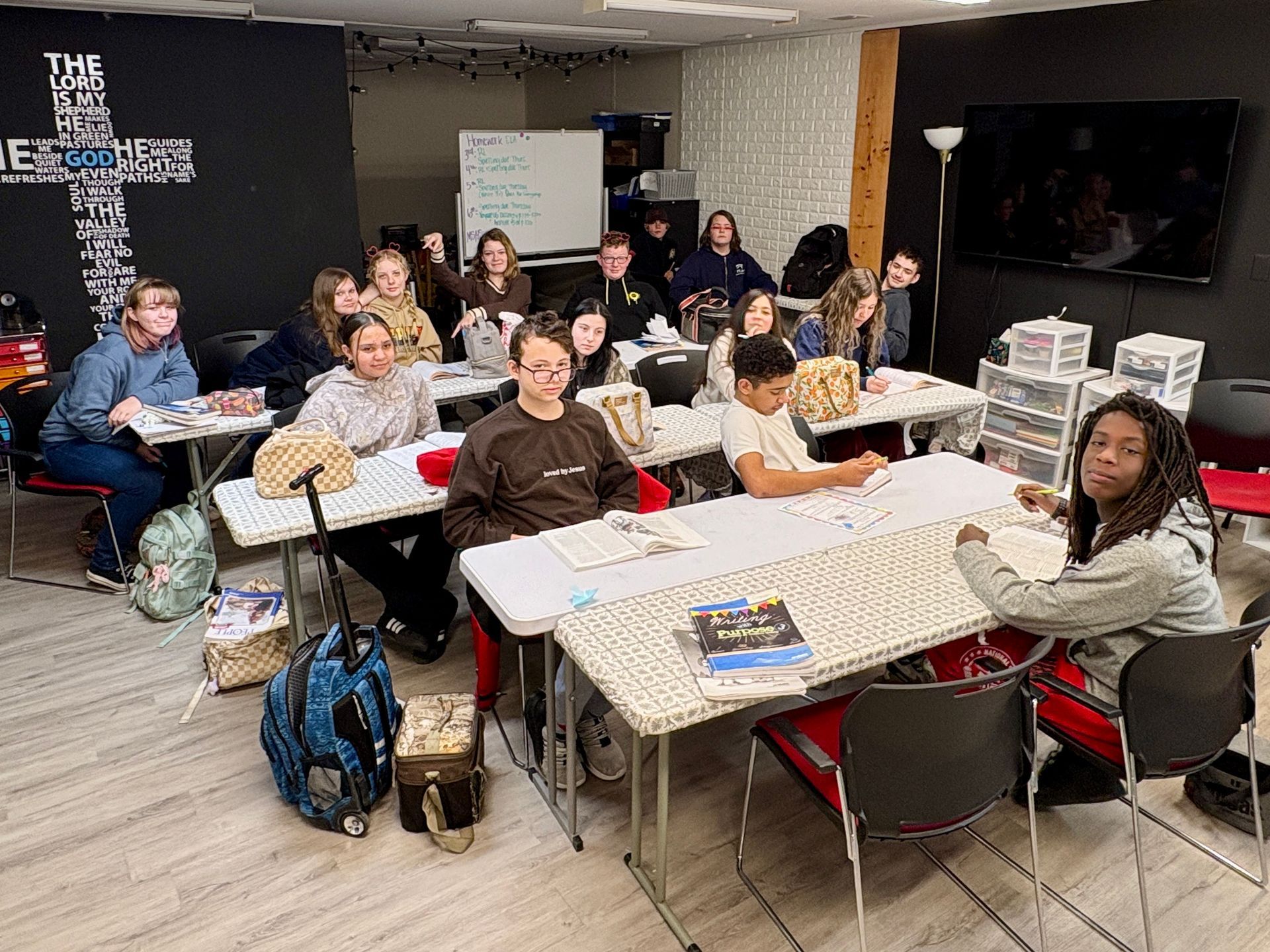 Three people in pajamas smiling indoors. One is wearing a Grinch outfit.