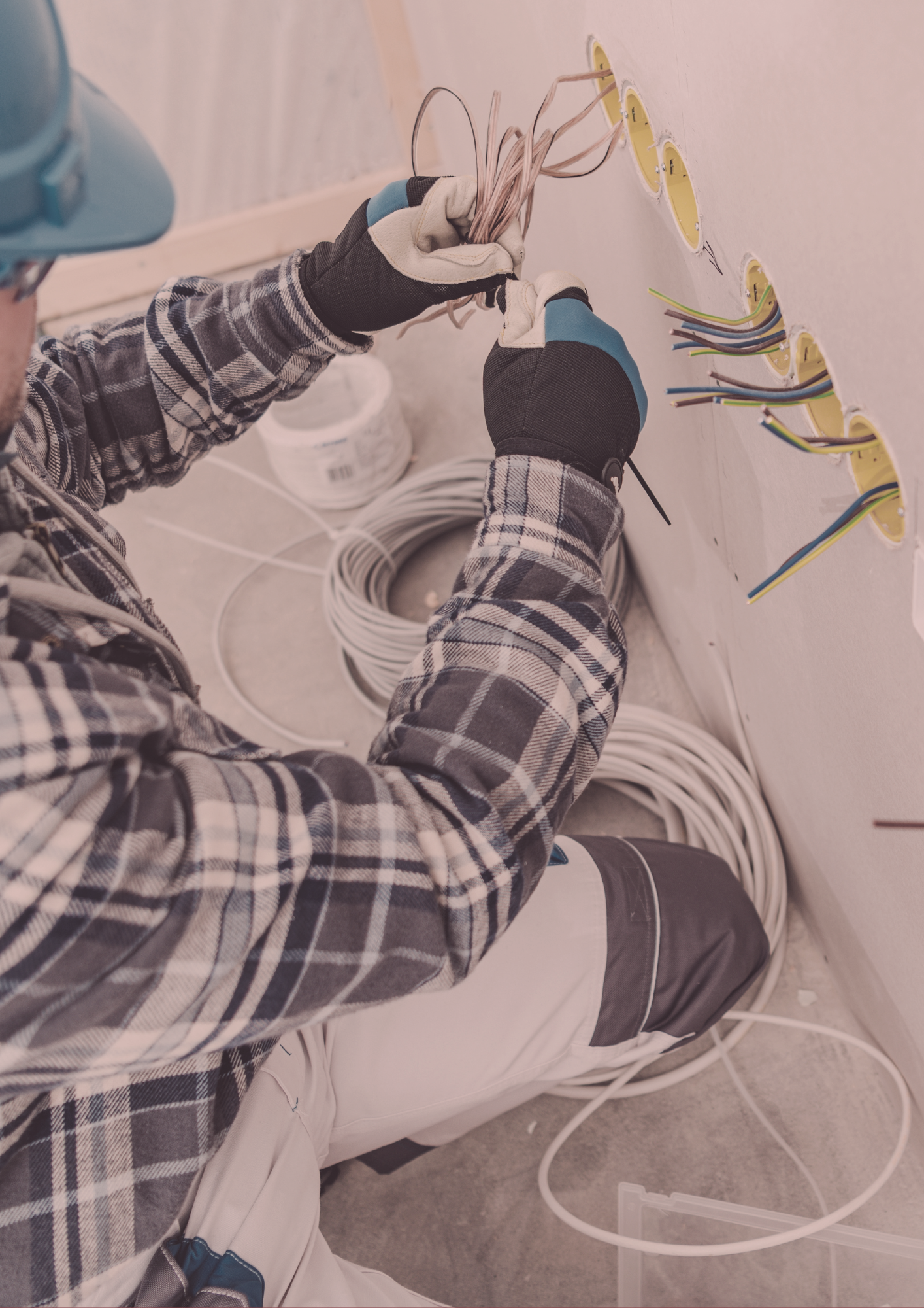 An electrician is working on a wall with a pair of scissors.