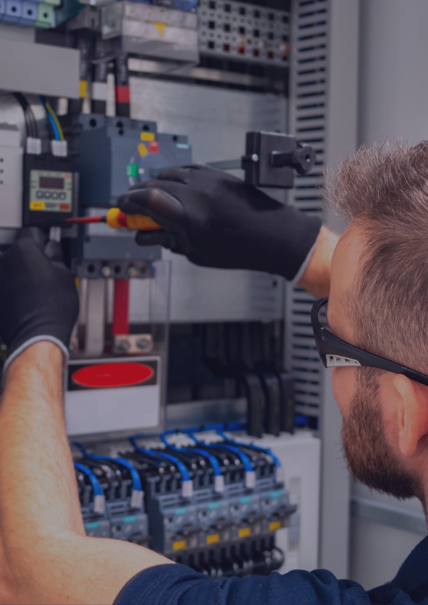 A man is working on an electrical box with a screwdriver.