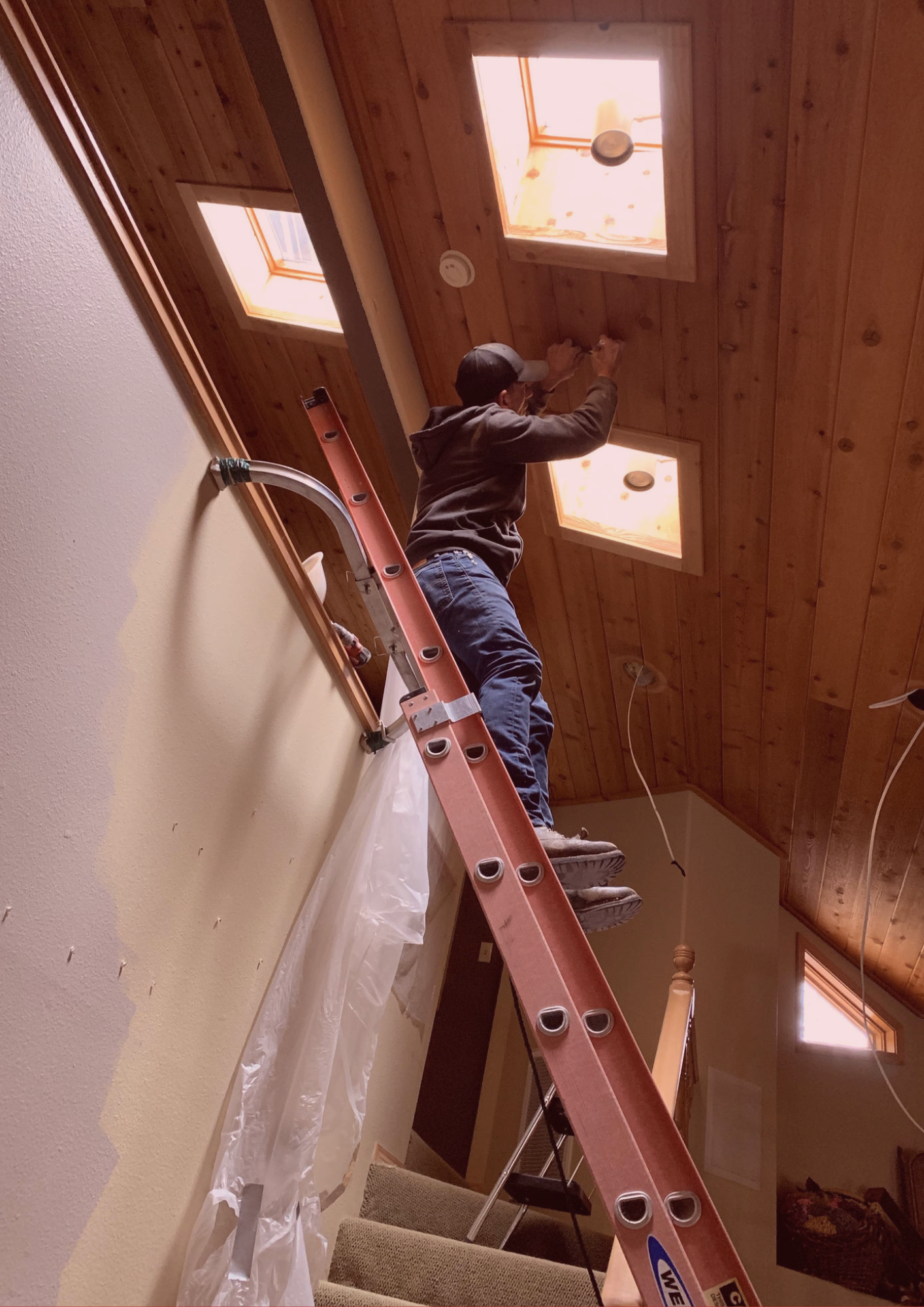 A man is standing on a ladder in a room.