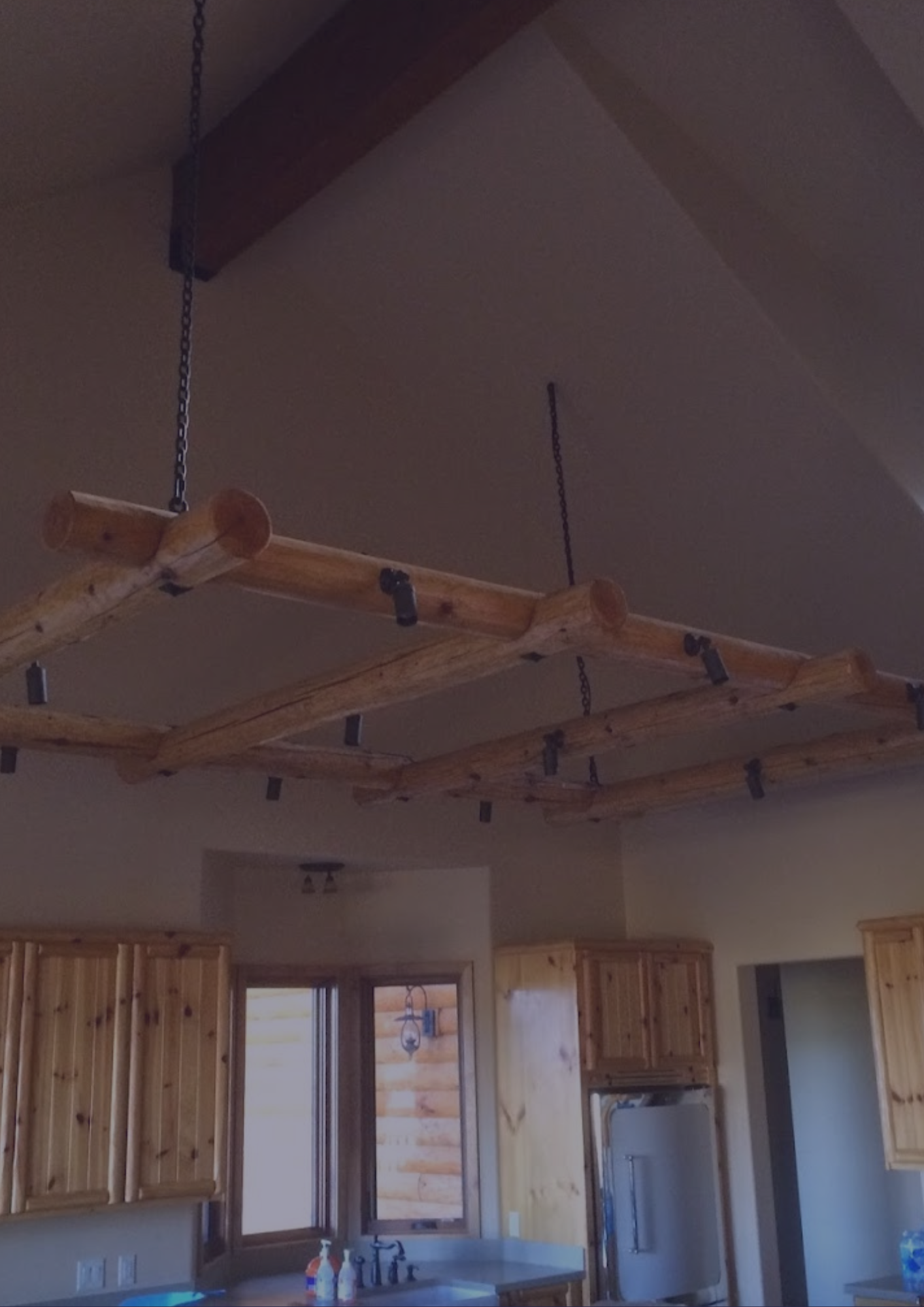 A kitchen with wooden cabinets and wooden beams hanging from the ceiling