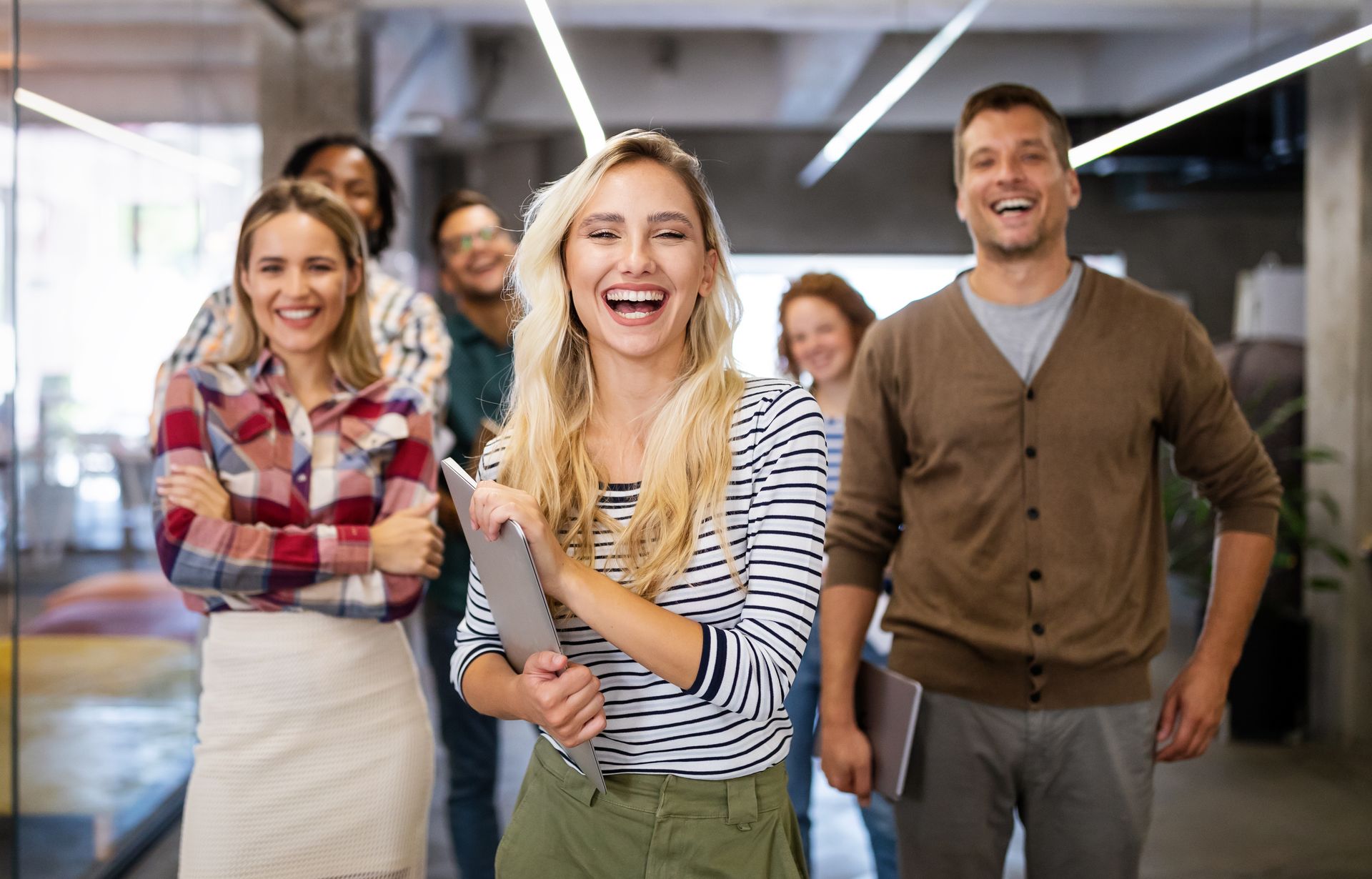 Group of people smiling and looking at the camera in a modern office.