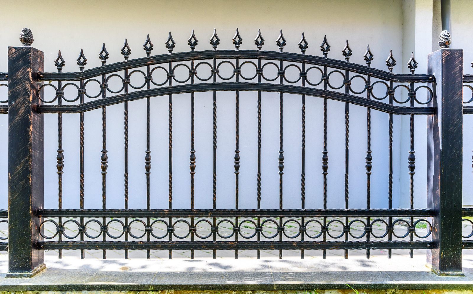 Gray metal balcony railing on a stucco building, against a cloudy sky.