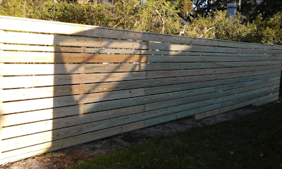 Horizontal wooden fence in outdoor setting with sun and shadow.