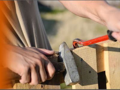 Person using a crowbar to pry wood apart.