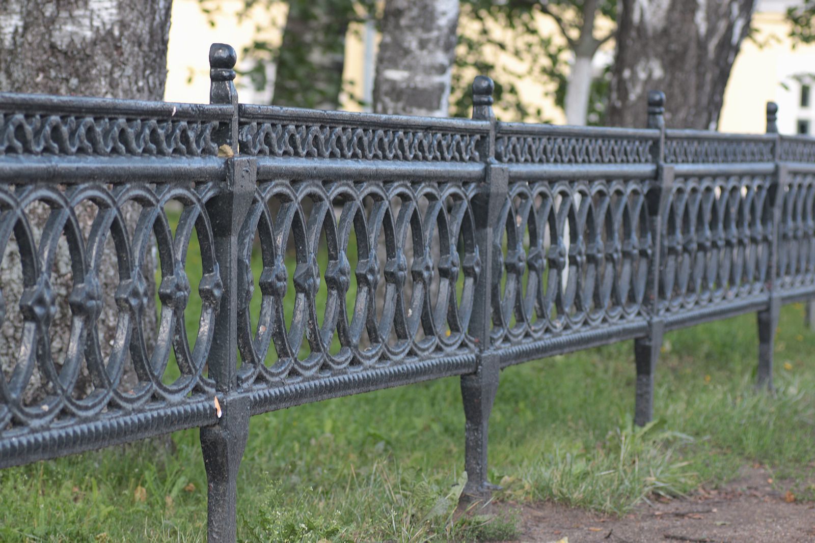 Person in gloves painting a white picket fence with a paintbrush.