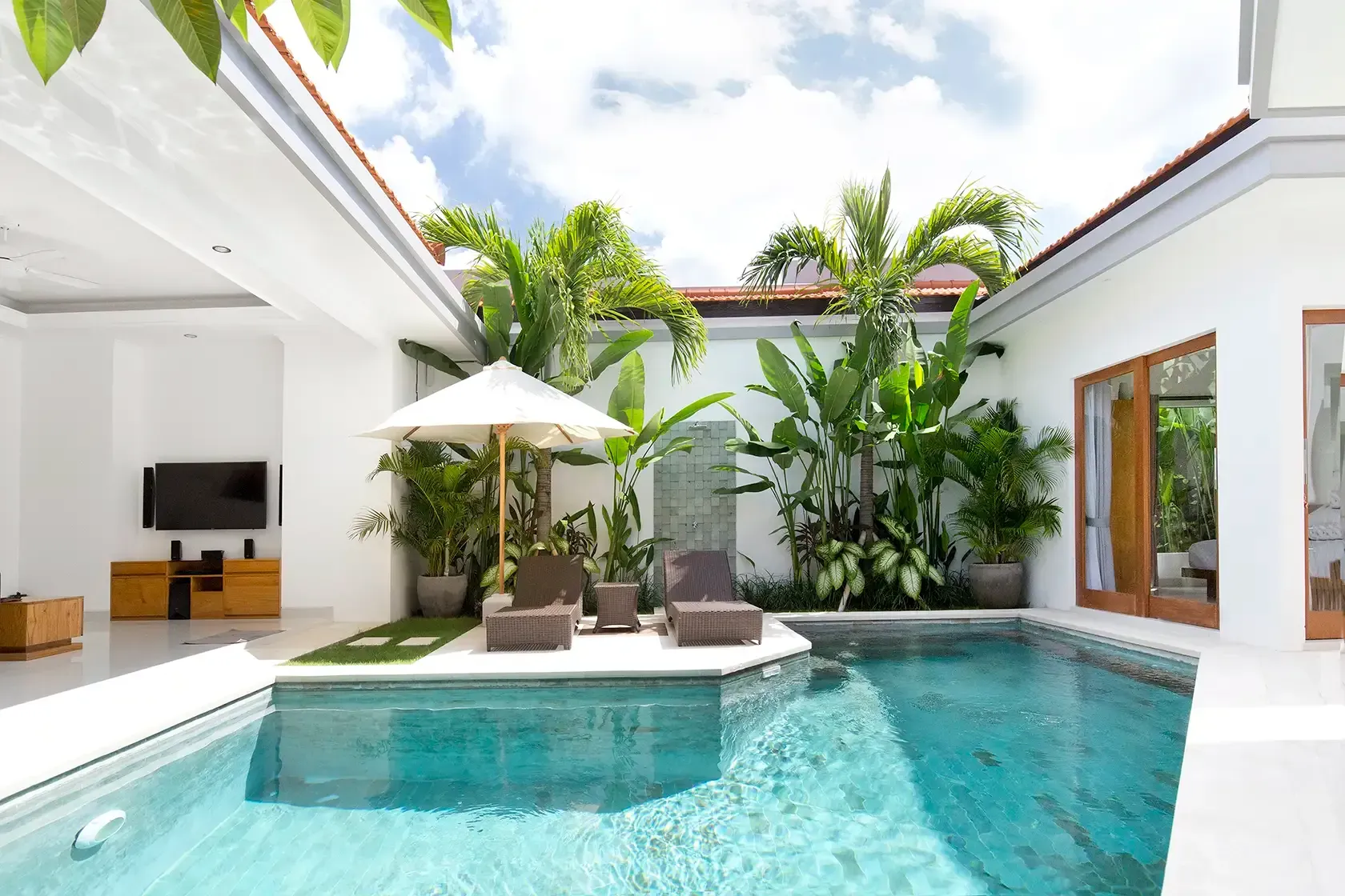 Private villa pool with two sunbeds and an umbrella